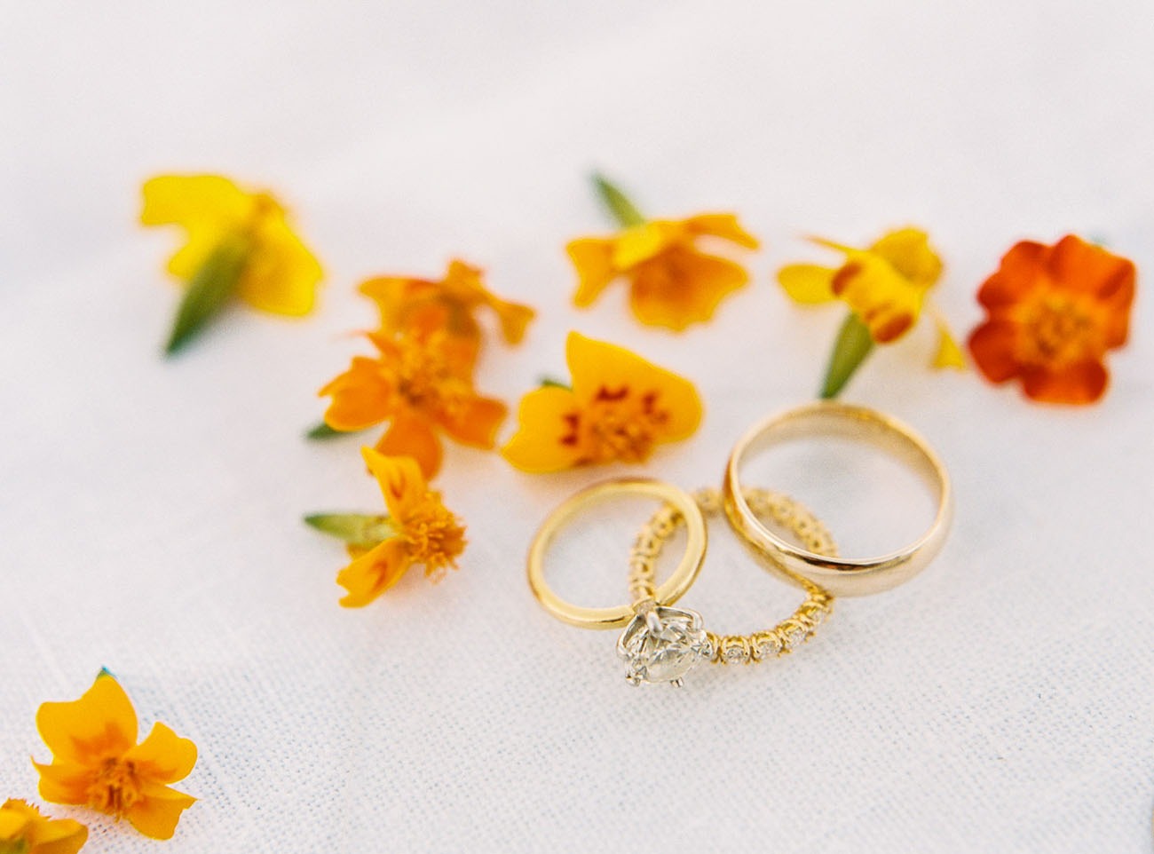 gold mens wedding band sitting beside orange flowers